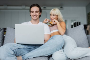 Kredi kartı ve dizüstü bilgisayarı olan bulanık ve mutlu çift online alışveriş yapıyor. 