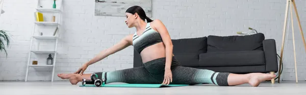 穿着运动服的孕妇在瑜伽垫 横幅上伸展着分裂的姿势 — 图库照片