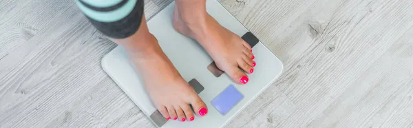 床上の体重を推定する裸足の女性のクロップドビューバナー — ストック写真