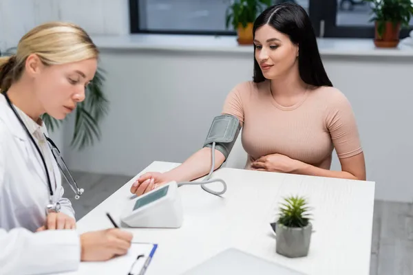 Blurred Doctor Writing Prescription Clipboard While Measuring Blood Pressure Pregnant — Stock Photo, Image