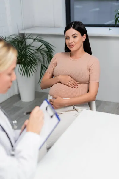 Gelukkig Zwanger Vrouw Kijken Naar Wazig Arts Schrijven Recept Klembord — Stockfoto