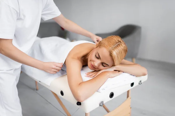 Professioneller Masseur Bedeckt Rücken Der Zufriedenen Frau Auf Massagetisch — Stockfoto