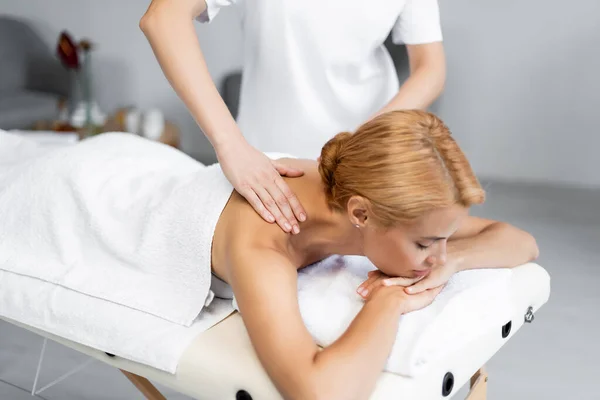 Massagista Fazendo Massagem Ombro Para Cliente Loiro Com Olhos Fechados — Fotografia de Stock