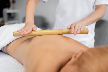 Profesyonel masörün, müşterinin arkasına bambu çubuğuyla masaj yapması kısmi görünümü