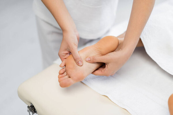 high angle view of masseur doing foot massage to client in spa center 