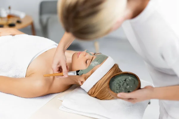 Verschwommene Kosmetikerin Trägt Gesichtsmaske Auf Frau Wellnesszentrum Auf — Stockfoto