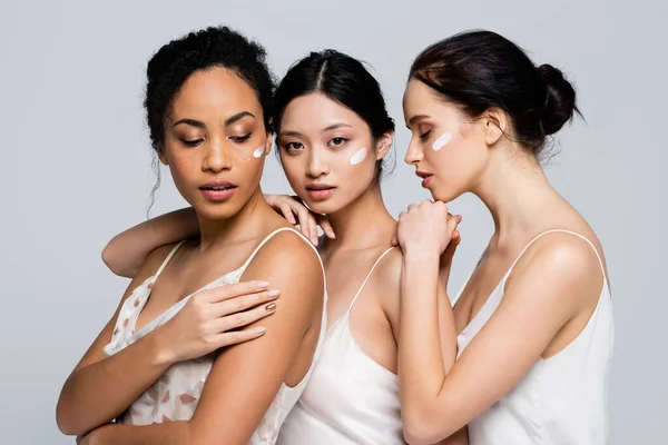 Багатоетнічні Жінки Косметичним Кремом Обличчях Обіймають Один Одного Ізольовані Сірому — стокове фото