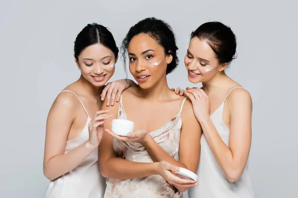 Interracial Women Hugging African American Friend Cosmetic Cream Isolated Grey — Stock Photo, Image