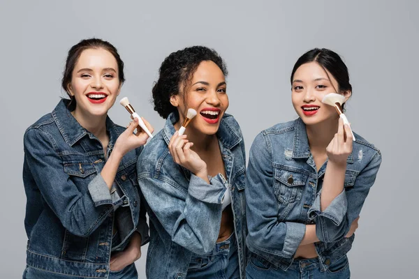 Happy Multicultural Women Red Lipsticks Holding Cosmetic Brushes Isolated Grey — Stock Photo, Image