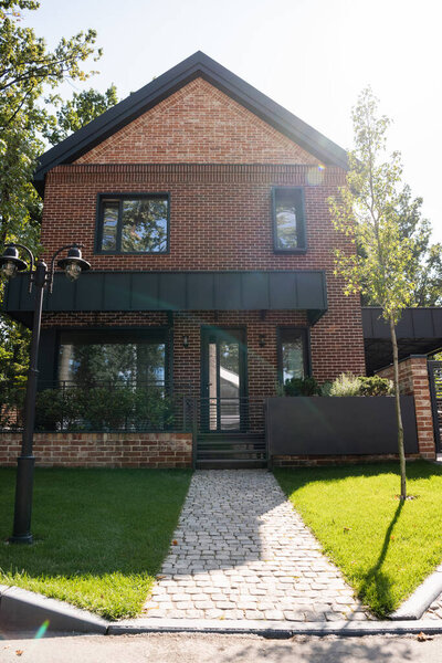 солнечный свет на зеленой лужайке возле современного дома 