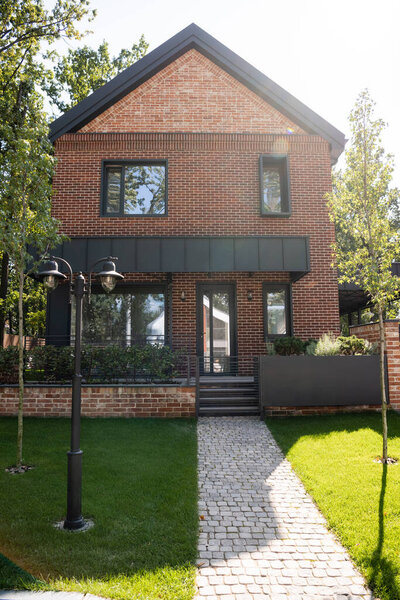 солнечный свет на зеленой лавке рядом с современным новым домом 