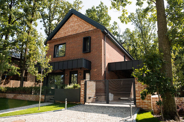 солнечный свет на современном доме рядом с зелеными деревьями на улице 