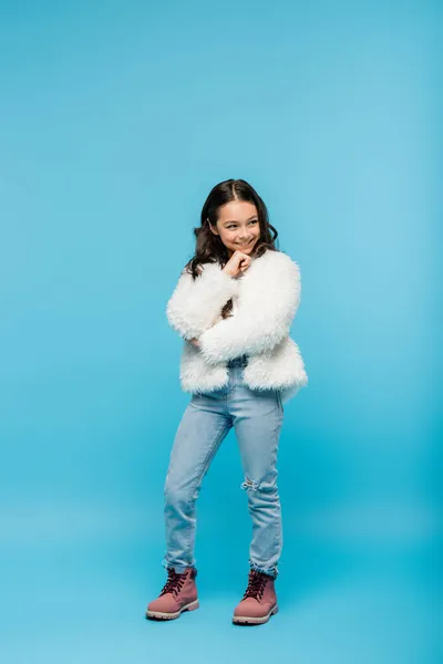 正の十代の女の子のフル長いですのFaux毛皮のジャケットと冬のブーツPosingオン青 — ストック写真