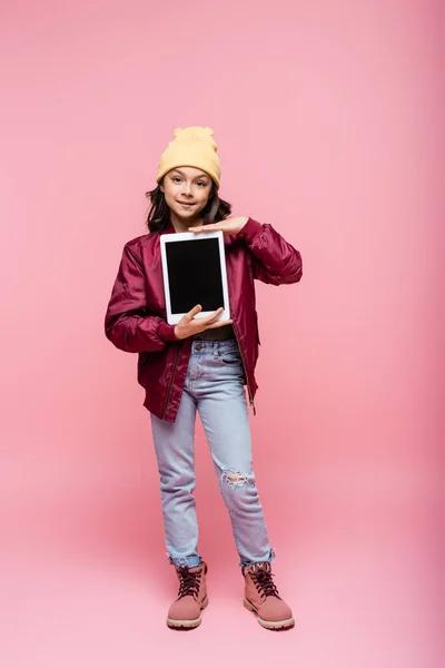 冬服の笑顔のPreteen女の子のフル長さ保持デジタルタブレットとともに空白の画面上ピンク — ストック写真