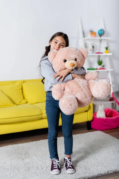 Zadowolony Nastolatek Dziewczyna Przytulanie Miękkie Zabawka Stojąc Dywanie Domu — Zdjęcie stockowe