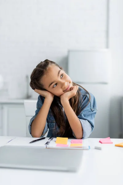 Verträumtes Schulkind Sitzt Neben Verschwommenem Laptop Und Notebook Hause — Stockfoto