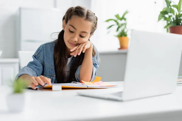 Criança Olhando Para Livro Cópia Perto Laptop Durante Trabalhos Casa — Fotografia de Stock