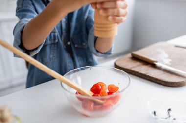 Mutfakta yemek pişirirken vişneli domatesleri çeşnilendiren bulanık çocuk manzarası 