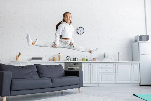 Cheerful Kid Doing Split While Jumping Couch Kitchen — Stock Photo, Image