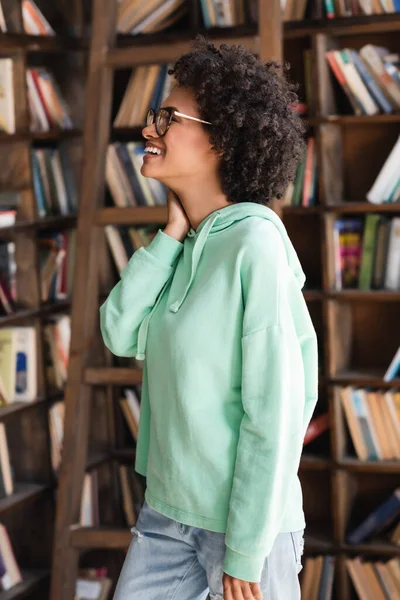 Χαρούμενος Αφροαμερικάνος Φοιτητής Γυαλιά Που Κοιτάζει Στο Ράφι Της Βιβλιοθήκης — Φωτογραφία Αρχείου