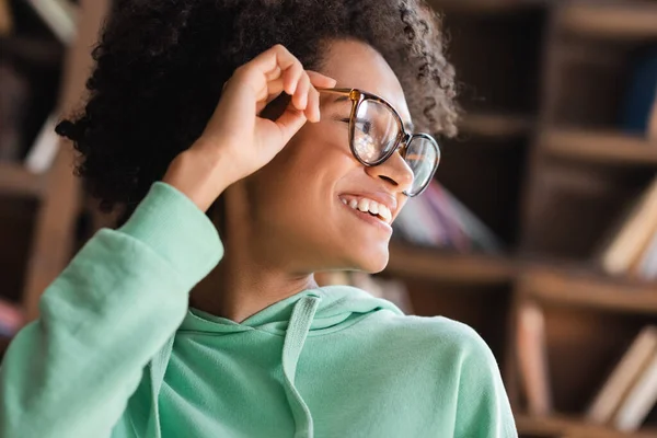 Positive African American Student Smiling While Adjusting Eyeglasses Looking Away — Stock Photo, Image