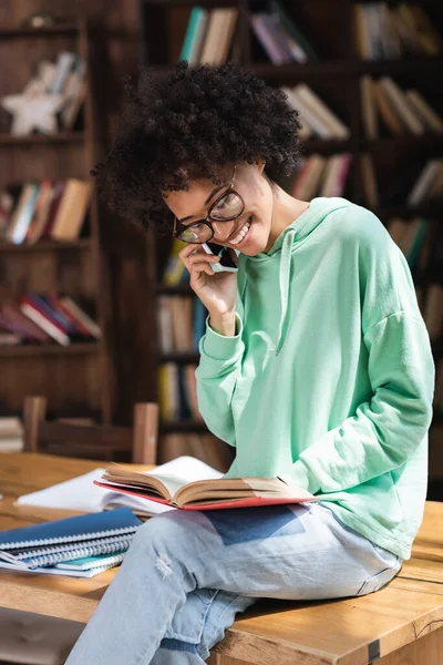 Alegre Africano Americano Estudiante Gafas Hablando Teléfono Celular Lectura Libro — Foto de Stock