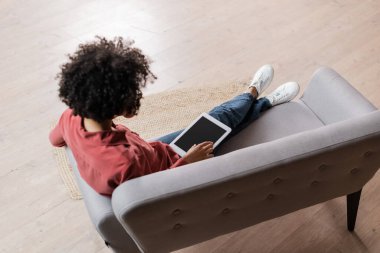 Beyaz ekranlı dijital tablet kullanan kıvırcık Afrikalı Amerikalı kadının yüksek açılı görüntüsü
