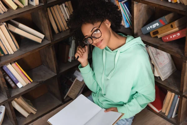 Alegre Afroamericano Estudiante Gafas Con Pluma Cuaderno Biblioteca — Foto de Stock