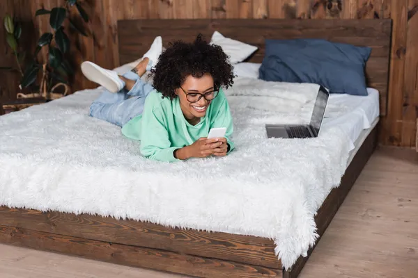 Happy African American Woman Eyeglasses Lying Bed While Using Smartphone — Stock Photo, Image