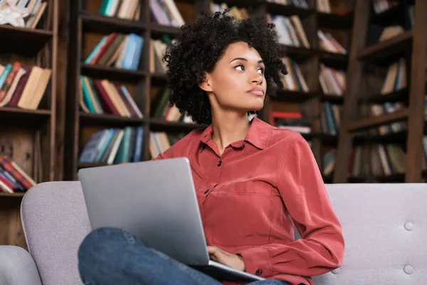 Mujer Afroamericana Distraída Sentada Sofá Con Ordenador Portátil Mirando Hacia — Foto de Stock