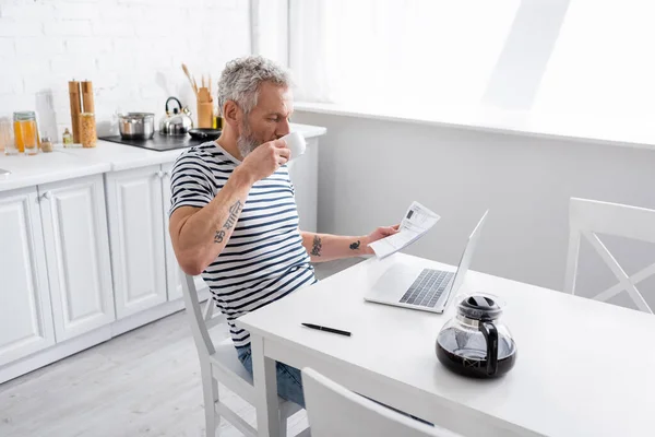 Hombre Sosteniendo Papeles Con Facturas Beber Café Cerca Computadora Portátil — Foto de Stock