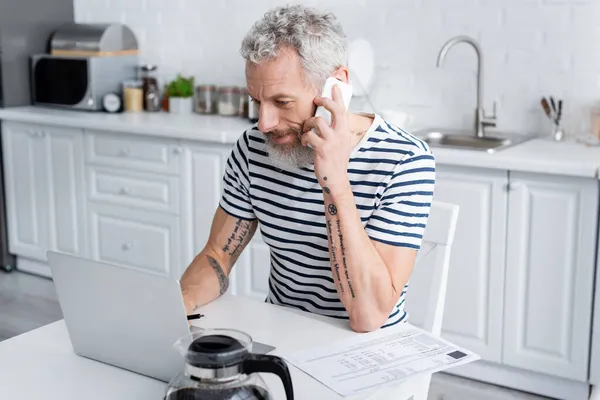 Hombre Hablando Teléfono Inteligente Uso Ordenador Portátil Cerca Facturas Café — Foto de Stock