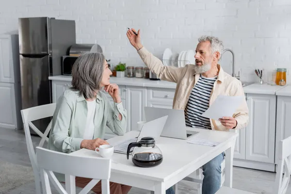 Mature Man Bills Talking Wife Laptops Coffee Kitchen — Stock Photo, Image