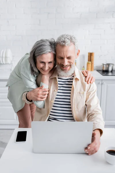 Middle Aged Woman Hugging Husband Gadgets Cup Coffee Kitchen — Stock Photo, Image