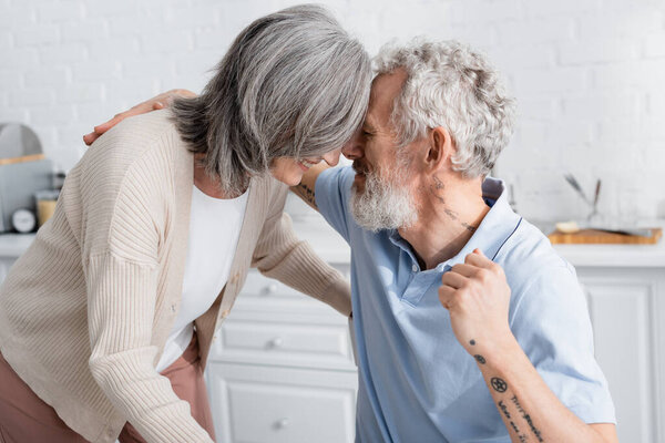 Mature man hugging smiling wife in kitchen 