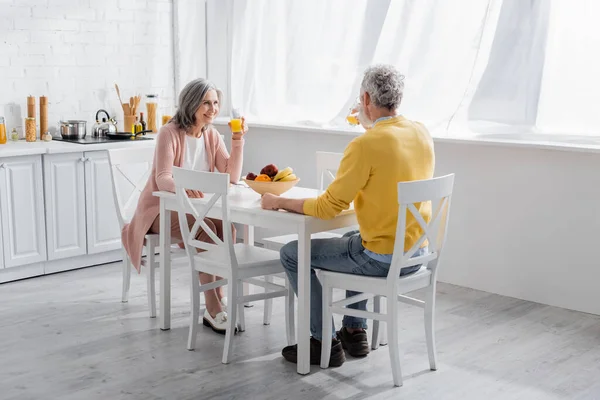 Mujer Sonriente Sosteniendo Vaso Jugo Naranja Cerca Las Frutas Marido — Foto de Stock