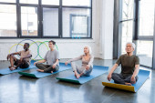 Ältere multiethnische Menschen praktizieren Yoga im Sportzentrum 