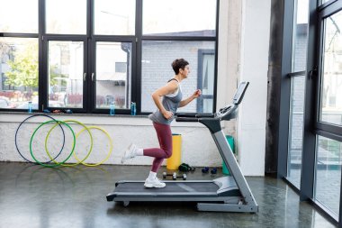 Spor merkezinde koşu bandında spor kadını eğitiminin yan görüntüsü 