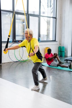 Spor salonunda direniş bandı ile yaşlı Asyalı sporcu eğitimi 