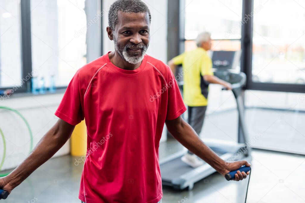 African american sportsman training with jump rope in sports center 