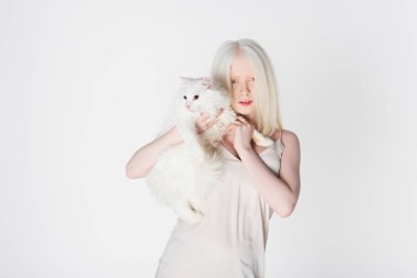 Kürklü kediyi tutan genç albino kadın beyaz üzerinde izole edilmiş. 