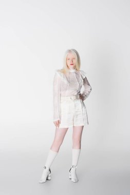 Beyaz arka planda dizlerinde çorapları olan son moda albino kadın. 