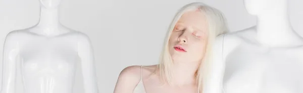 Albinoska Kobieta Zamkniętymi Oczami Stojąca Pobliżu Manekina Wyizolowana Białym Sztandarze — Zdjęcie stockowe