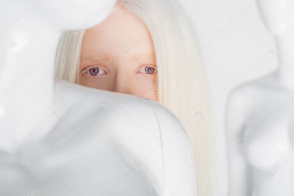 Albino woman looking at camera near mannequin isolated on white 