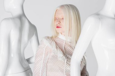 Beyaz renkli mankenlerin yanında duran albino model. 