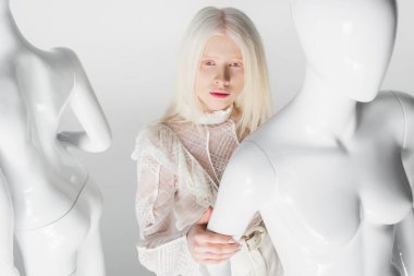 Bluzlu genç albino model beyaz mankenin yanında poz veriyor. 