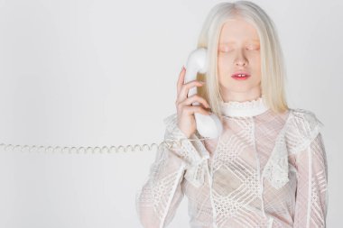 Gözleri kapalı, telefonda konuşan, beyaz tenli albino kadın. 
