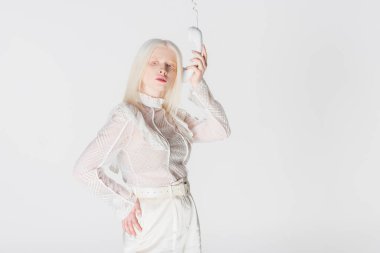 Şık bir albino kadın telefon ahizesiyle poz veriyor.