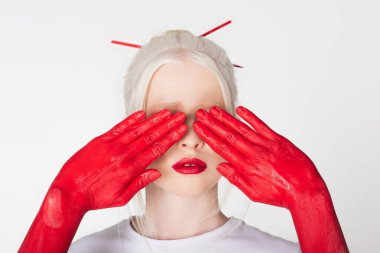 Female hands in paint covering eyes of albino model isolated on white clipart