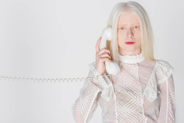 Albino woman talking on telephone and looking at camera isolated on white 